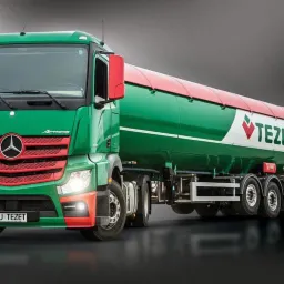 Ciężarówka Mercedes-Benz Actros z cysterną w barwach zieleni i czerwieni, z logo firmy TEZET, na ciemnym tle.