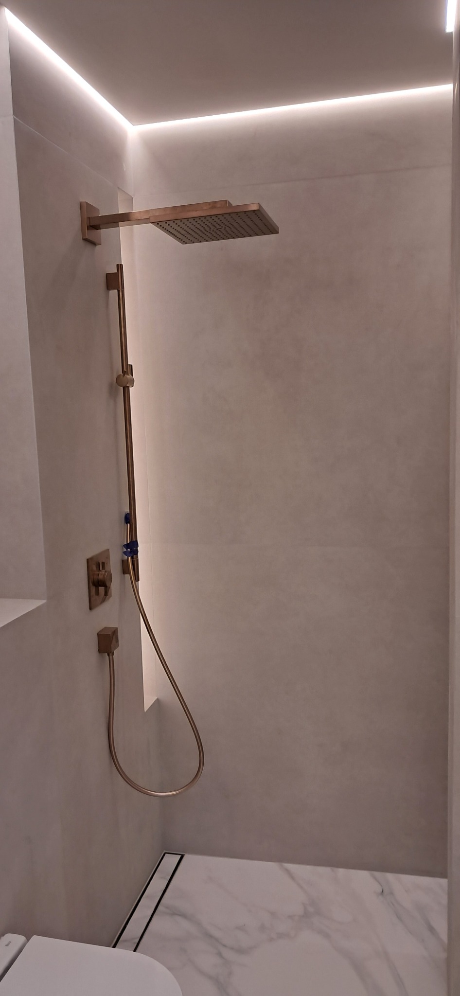 Nowoczesna kabina prysznicowa z deszczownicą w odcieniach miedzi, minimalistyczne wykończenie, subtelne oświetlenie LED, marmurowa posadzka.