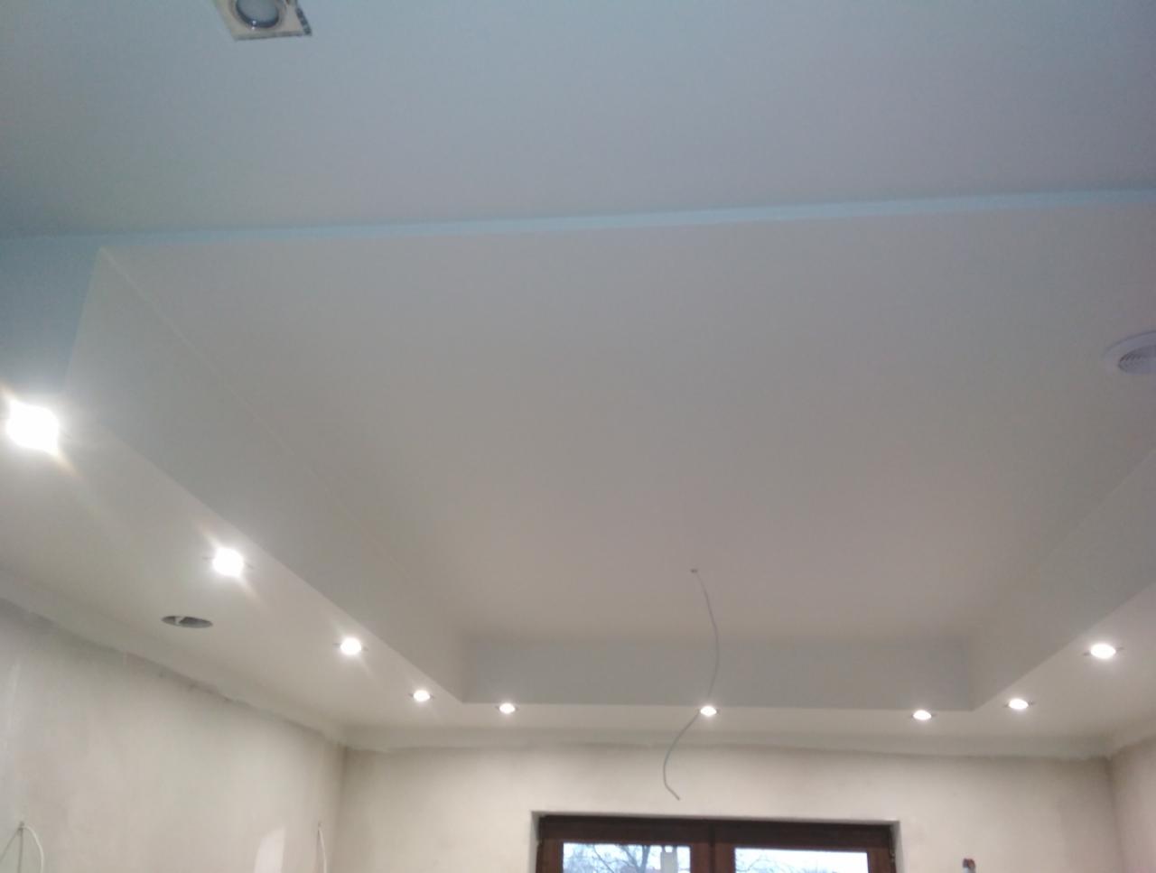 Biały sufit podwieszany z wbudowanym oświetleniem punktowym, widok z dołu, widoczne niedoskonałości na ścianach przed malowaniem.