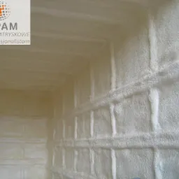 Poddasze po natrysku pianki poliuretanowej, widoczne nierówności i struktura izolacji, narożnik pomieszczenia.