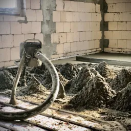 Aplikacja mokrego jastrychu za pomocą pompy na ogrzewanie podłogowe w surowym wnętrzu budynku.