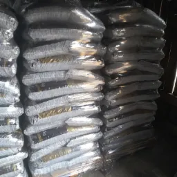 Stosy worków na paletach, owinięte folią stretch, prawdopodobnie w magazynie; widoczne etykiety na workach.