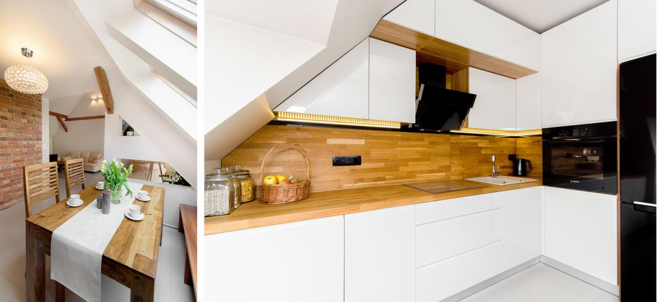 Nowoczesna kuchnia z białymi szafkami i drewnianym blatem, widok na jadalnię z drewnianym stołem i ceglaną ścianą, oświetlona światłem dziennym z okna dachowego.