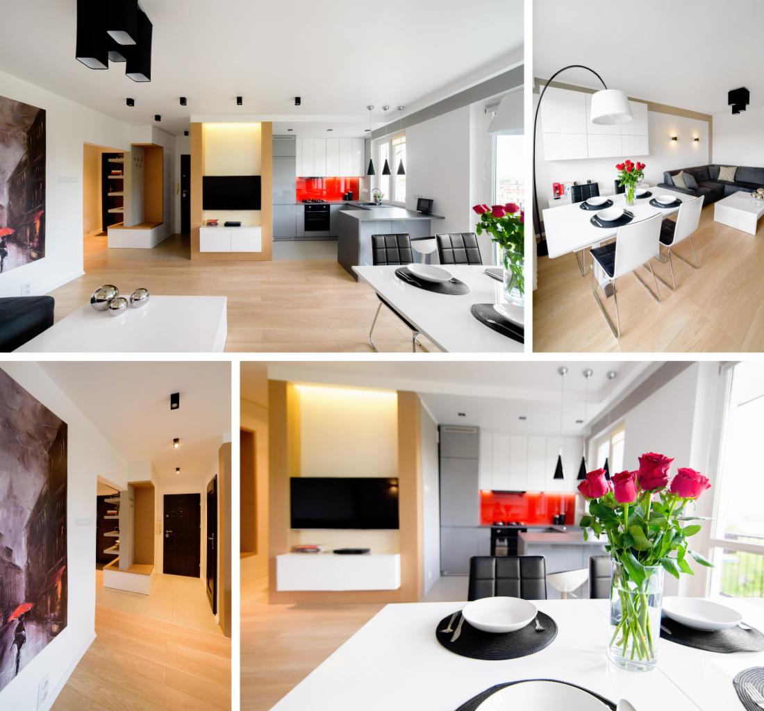 Nowoczesne wnętrze mieszkania z otwartą kuchnią, jadalnią i salonem, utrzymane w jasnej kolorystyce z akcentami czerwieni, drewniana podłoga, minimalistyczne meble i oświetlenie.