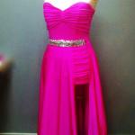 Jaskraworóżowa suknia wieczorowa bez ramiączek z drapowaniem w górnej części i paskiem z błyszczących kamieni, widoczny rozporek eksponujący nogę.