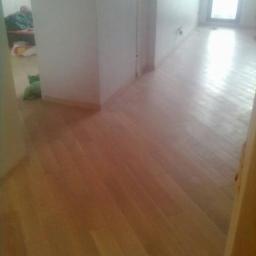 Ruthenia-Group Sp.z o.o - Jasne drewniane panele podłogowe ułożone wzdłuż długiego, pustego korytarza z białymi ścianami w nowym domu.