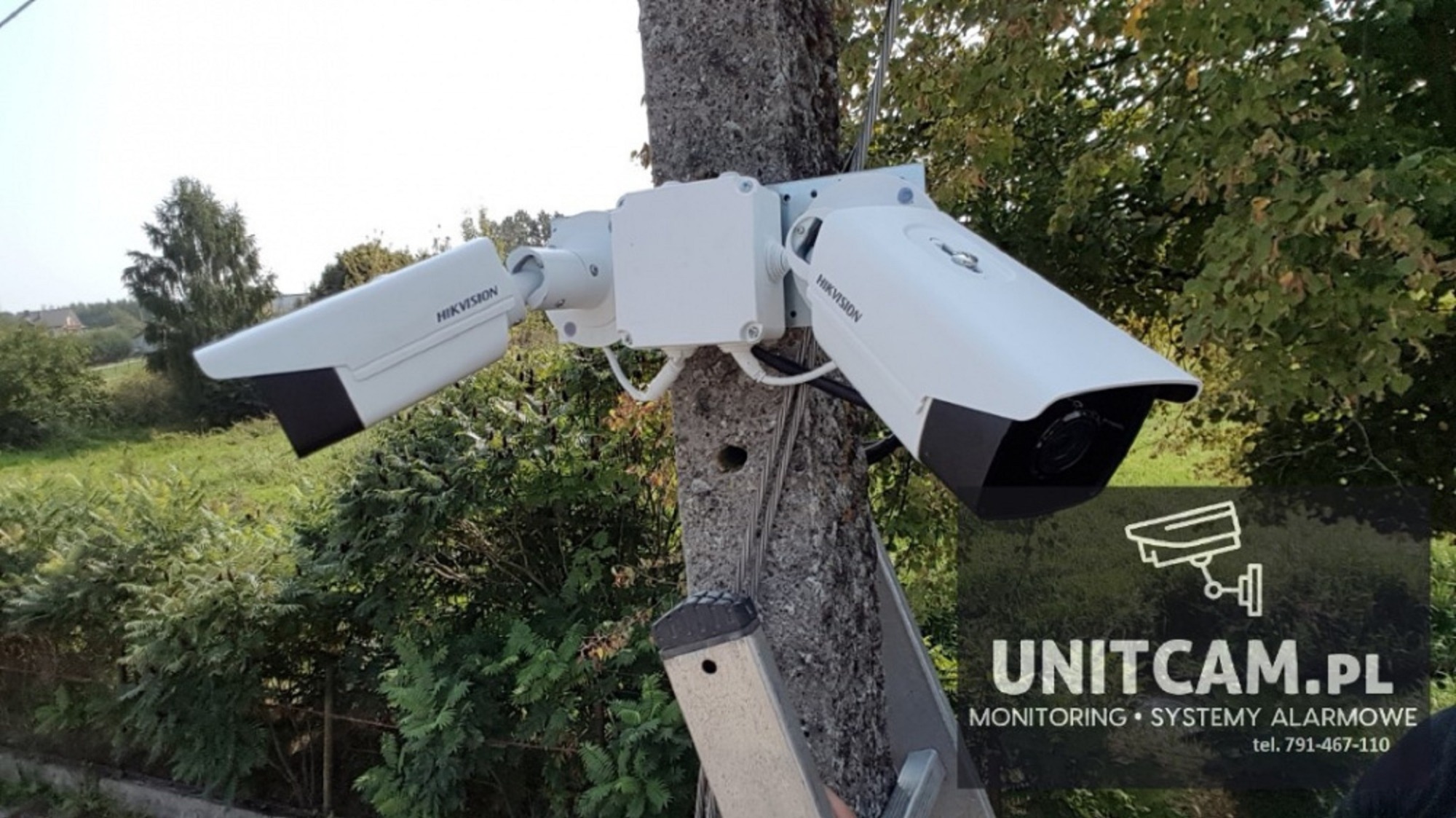 Dwie kamery monitoringu IP marki Hikvision zamontowane na słupie w Szydłowcu, widoczne okablowanie i drabina.