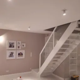 Białe schody z drewnianą konstrukcją i szklanymi balustradami w nowoczesnym wnętrzu, widoczne półki w konstrukcji schodów.