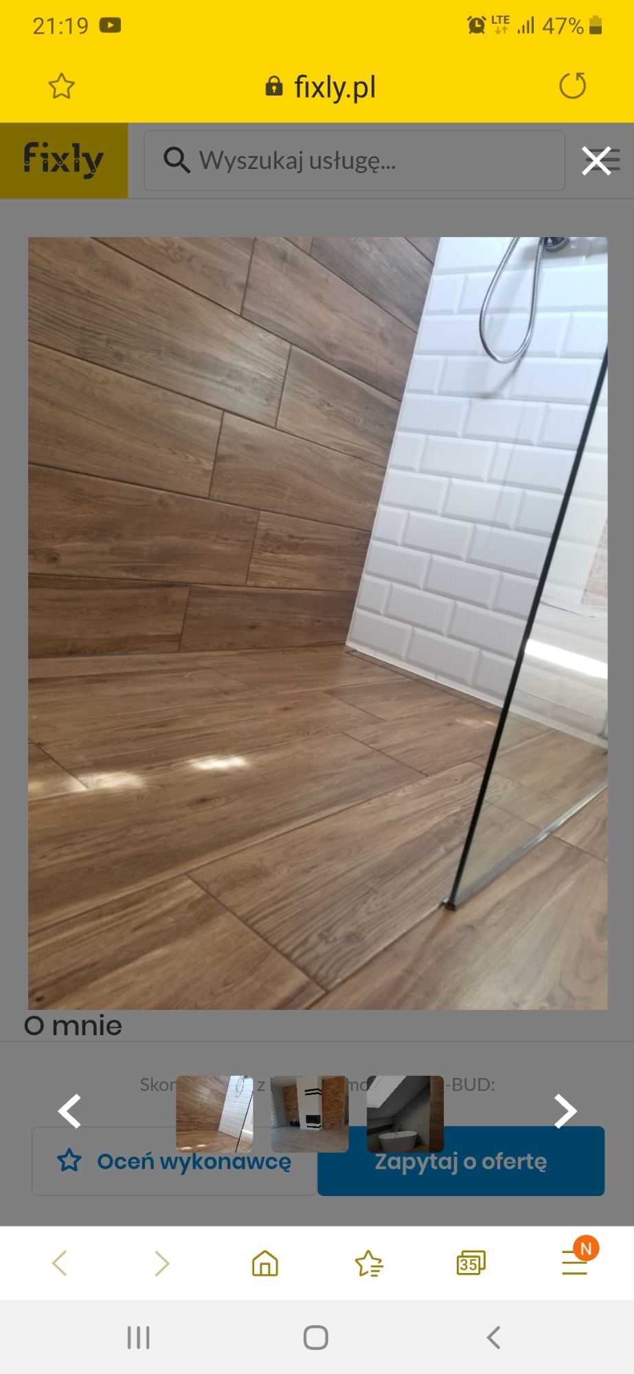 Ukończona łazienka z drewnopodobną podłogą z płytek i białą ścianą z płytek typu metro, oddzielona szklaną ścianką prysznicową.