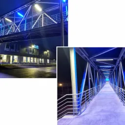 Zewnętrzny, oświetlony na niebiesko, stalowy łącznik pomiędzy budynkami Autoliv w Jelczu Laskowicach, widok z zewnątrz i od wewnątrz.