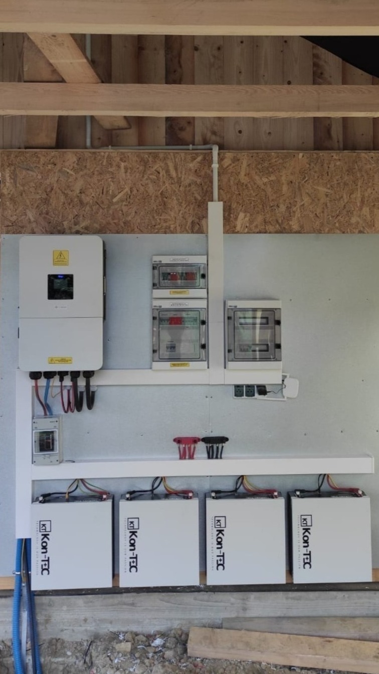 Kompletna instalacja magazynu energii Kon-TEC z inwerterem i rozdzielnicami, zamontowana na ścianie z płyt OSB w surowym wnętrzu budynku.