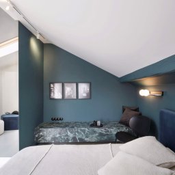 Simple Form Renia Bartoszek - Stylowa sypialnia na poddaszu z zielonymi ścianami i marmurowym siedziskiem. Trzy czarno-białe zdjęcia nad siedziskiem. Minimalistyczna lampka ścienna.