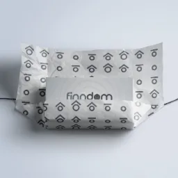 Wizytówka firmy Finndom zapakowana w papier ozdobny z powtarzalnym wzorem graficznym, przewiązana cienkim sznurkiem, na jasnym tle.