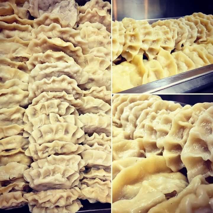 Taca pełna gotowanych pierogów z dekoracyjnym brzegiem, ułożonych w rzędach, widok z góry.