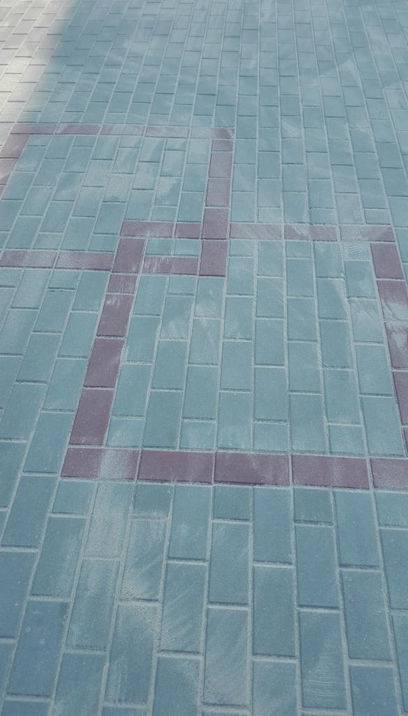 Niebiesko-szare kostki brukowe z bordurowym wzorem w Psarach, świeżo po ułożeniu, widoczne delikatne zabrudzenia po piasku.