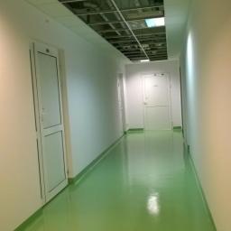 Art&Decor - Korytarz z zieloną, błyszczącą posadzką żywiczną, widoczna instalacja pod sufitem podwieszanym.