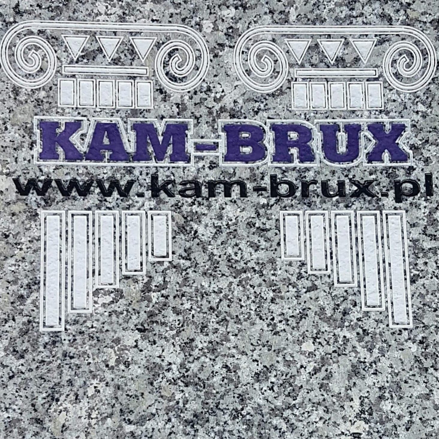 Szary granit z wygrawerowanym logo firmy Kam-Brux, zawierającym motywy architektoniczne i adres strony internetowej.