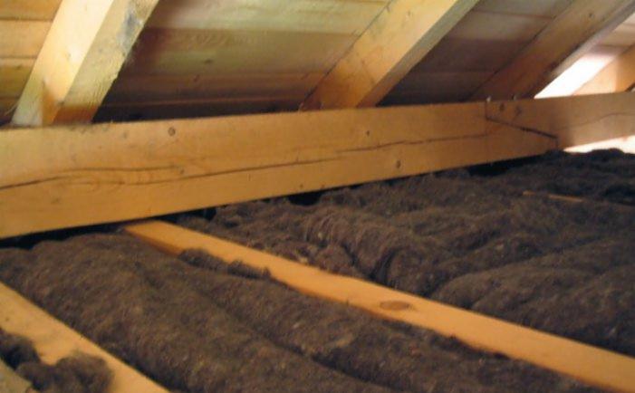 Ocieplenie poddasza z wykorzystaniem izolacji z naturalnej wełny owczej, widoczne drewniane krokwie i legary.
