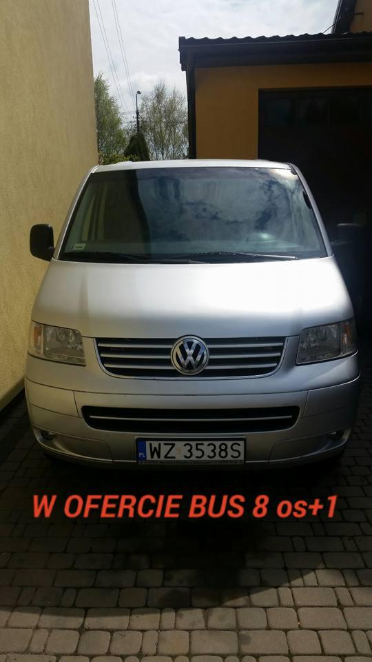 Srebrny Volkswagen Transporter T5 zaparkowany przed budynkiem, widoczne tablice rejestracyjne WZ 3538S i napis 'W ofercie bus 8 os+1'.