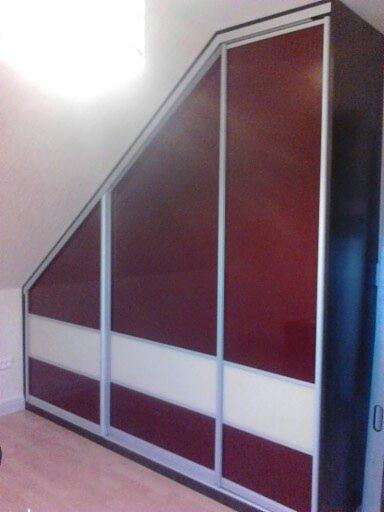 Szafa przesuwna w zabudowie pod skosem dachu, z panelami w kolorze burgundowym i białym, srebrne ramy, widoczne gniazdka elektryczne na ścianie.