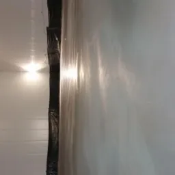 Przygotowane pomieszczenie z folią ochronną na ścianie, gotowe do prac związanych z wylewaniem posadzki.