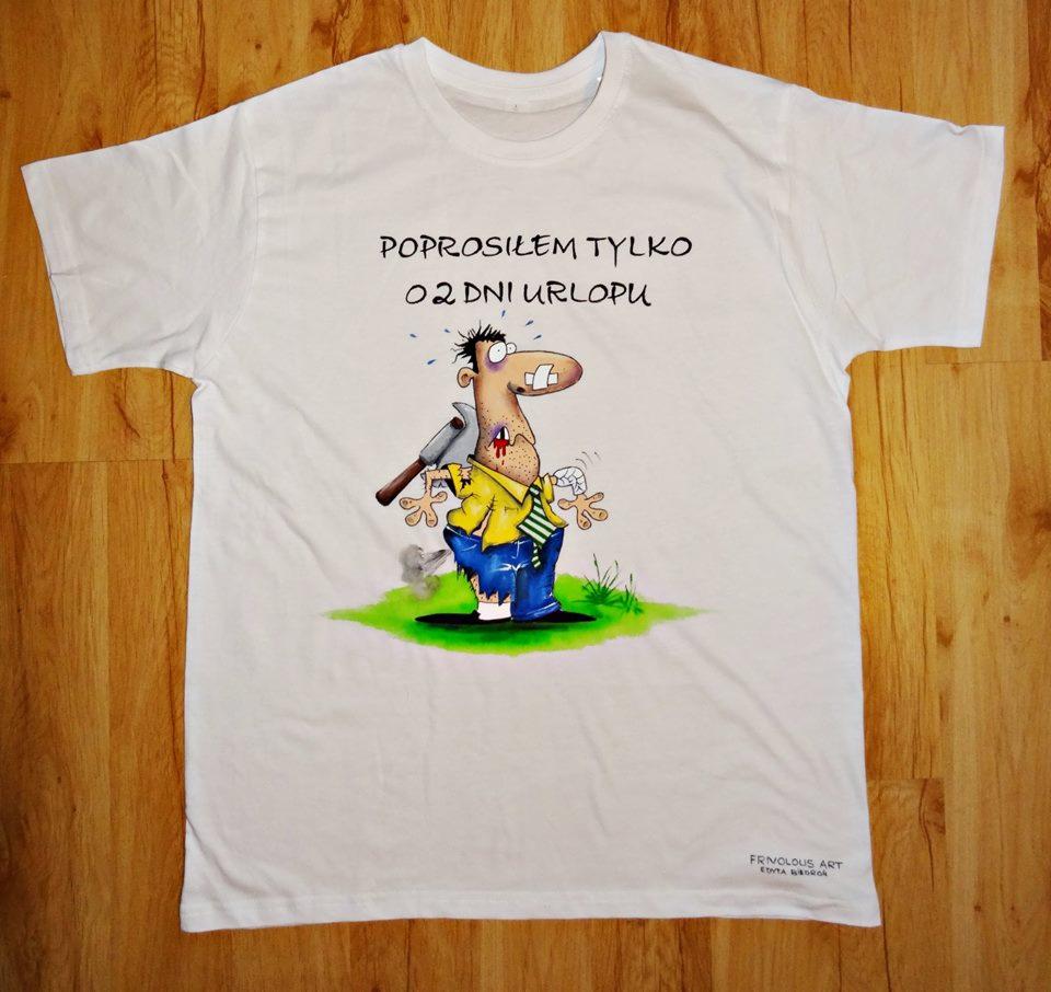Biała koszulka z humorystycznym nadrukiem przedstawiającym zmęczonego mężczyznę z siekierą w plecach i napisem 'Poprosiłem tylko o 2 dni urlopu', leżąca na drewnianym podłożu.
