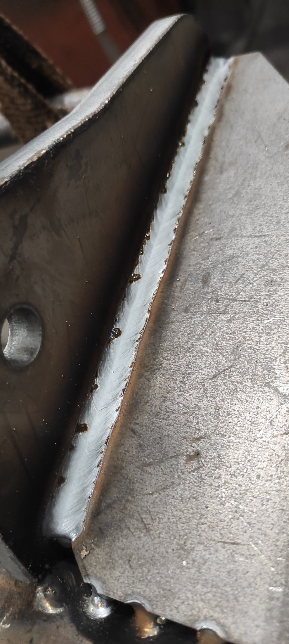 Spoina wykonana w Białymstoku: zbliżenie na świeżo zespawane elementy metalowe, widoczna struktura spoiny i drobne odpryski.