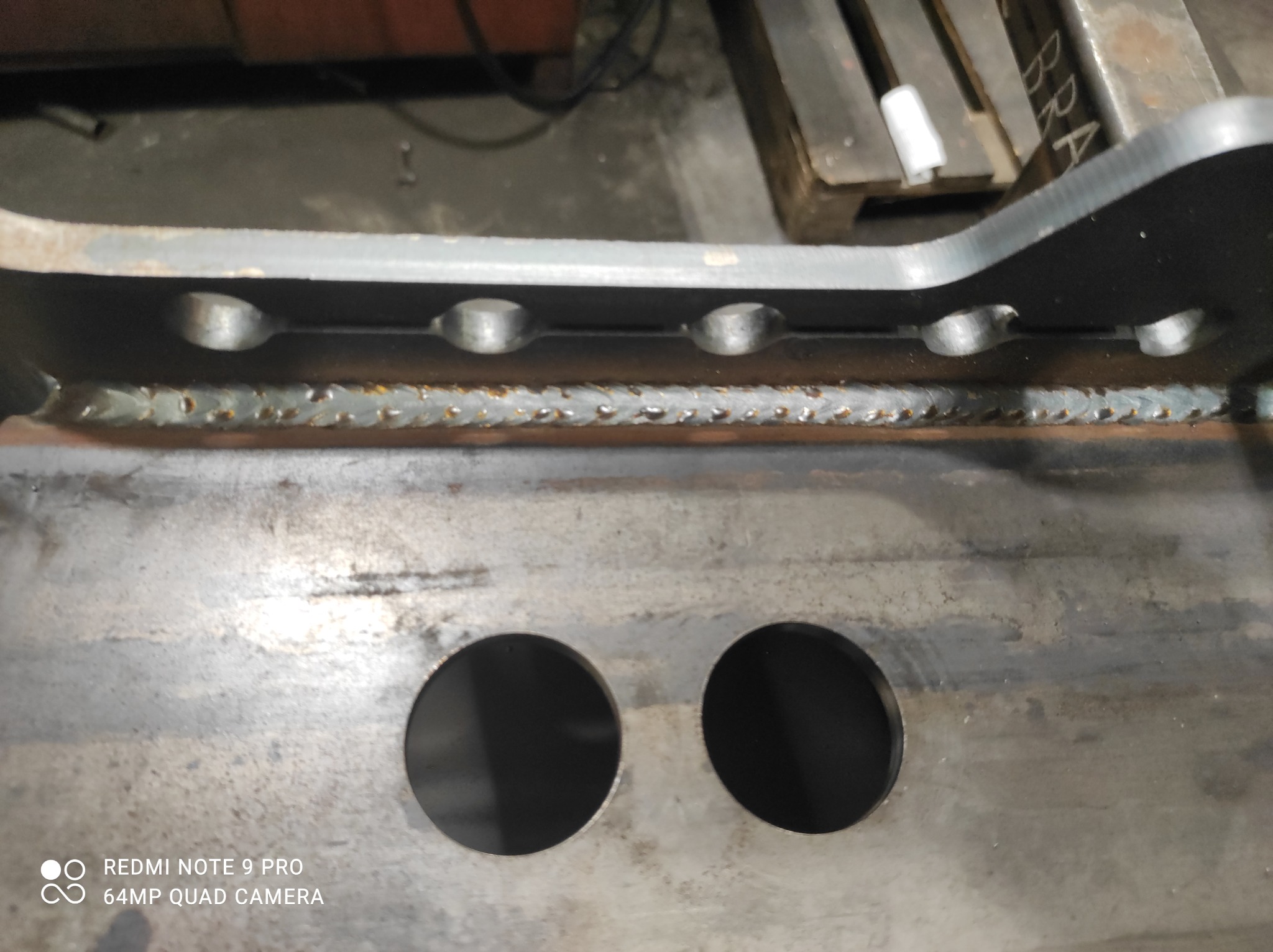 Metalowy element konstrukcyjny z widocznymi spawami i otworami, ujęcie z bliska, ukazujące detale wykonania.