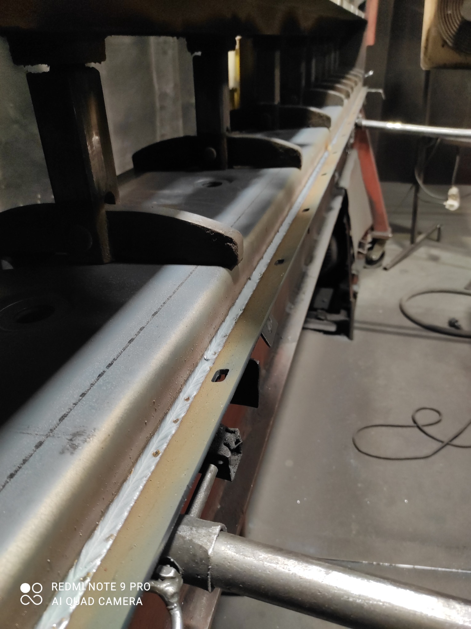 Spoina na metalowej konstrukcji, widoczne ślady po spawaniu, konstrukcja wsparta na kozłach.