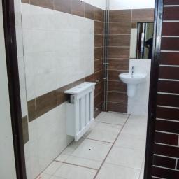 Rem-Bud Bartosz Żemła - Wyremontowana łazienka z białymi i brązowymi płytkami, białą umywalką na postumencie i grzejnikiem dekoracyjnym z białymi szczebelkami.