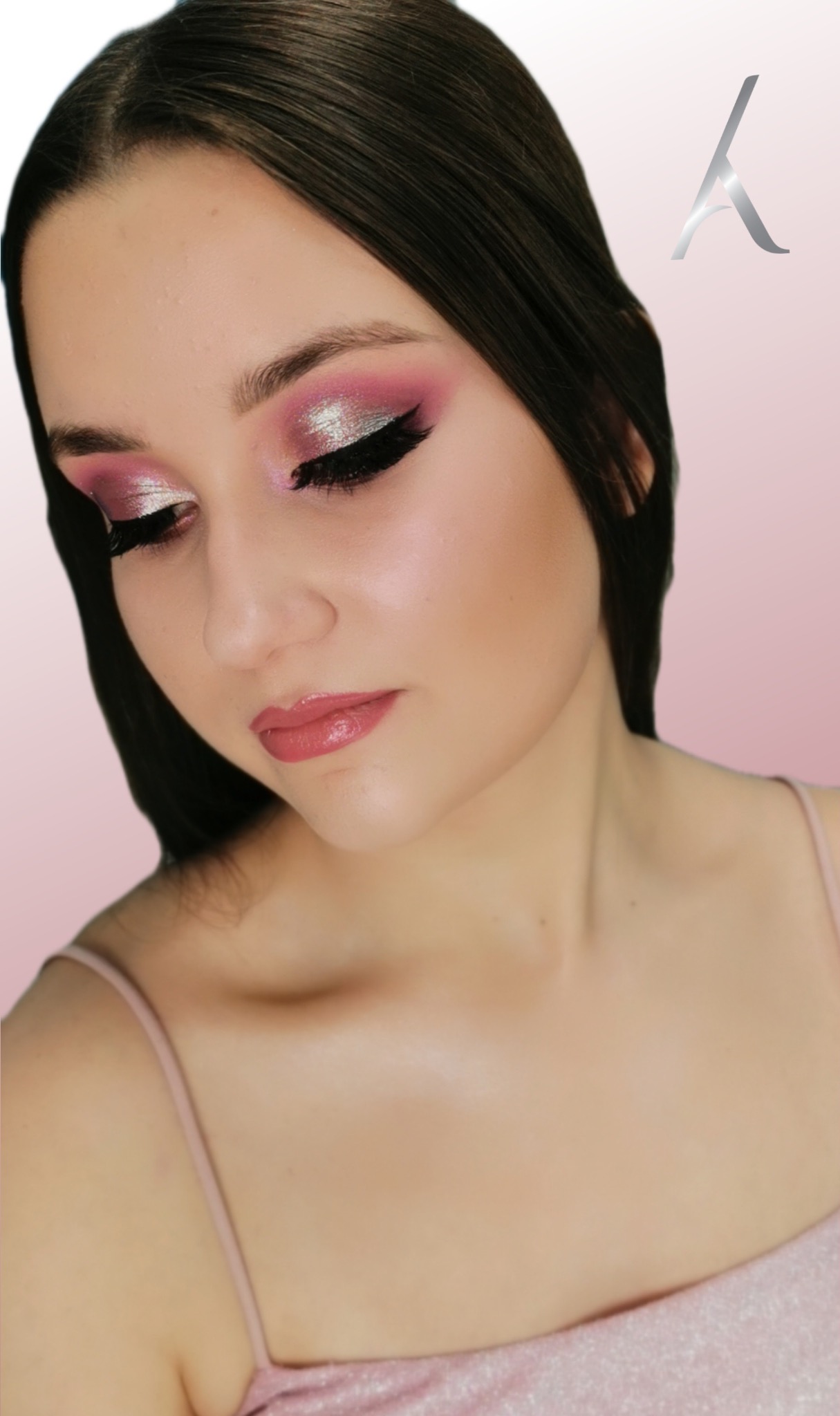 Portret kobiety z intensywnym, różowo-srebrnym makijażem oczu i błyszczącymi ustami na rozmytym, różowym tle.