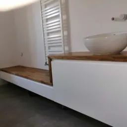 Nowoczesna łazienka z drewnianym blatem, asymetryczną umywalką i grzejnikiem drabinkowym