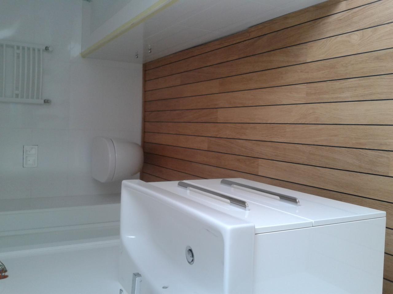 Nowoczesna łazienka z drewnianą okładziną ścienną, białą armaturą i minimalistycznym designem.