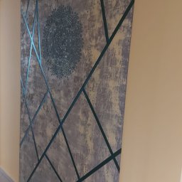 Damian Kanik Wykończenia wnętrz - Dekoracyjna ściana z szarym tłem, geometrycznymi zielonymi liniami i okrągłym, ozdobnym motywem w centrum. Element wystroju wnętrza z bliska.