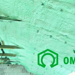 Rehouse MK - Poddasze z widoczną konstrukcją drewnianą i instalacją elektryczną pokryte warstwą izolacyjnej pianki poliuretanowej, z naniesionym logo firmy wykonawczej OMEGAPUR.