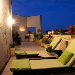 Rehouse MK - Umeblowany taras na dachu z dwoma leżakami, stolikiem, roślinami w donicach, oświetleniem ściennym i nocnym niebem w tle.