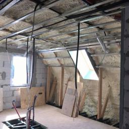 Pro-Bud system - Poddasze w trakcie adaptacji: ocieplenie pianą PUR na skosach dachu, metalowa konstrukcja pod sufitem, instalacje wodne wystające z podłogi, okno dachowe wpuszczające jasne światło.