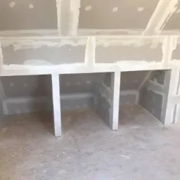 Niewykończona wnęka z płyt kartonowo-gipsowych w poddaszu, szpachlowana, gotowa do malowania, widoczne niedoskonałości na podłodze.