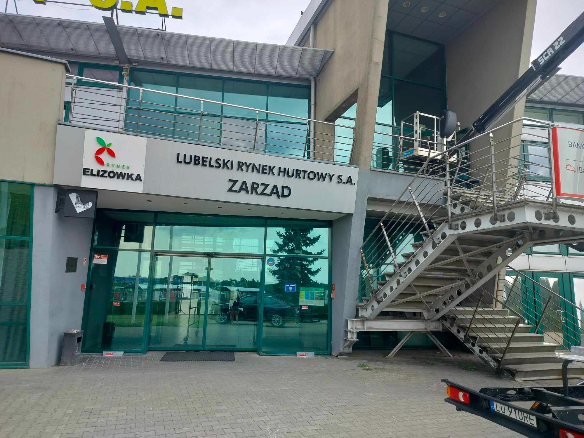 Budynek Lubelskiego Rynku Hurtowego S.A. z podnośnikiem koszowym przy oknach, prawdopodobnie podczas prac konserwacyjnych elewacji lub szyb.