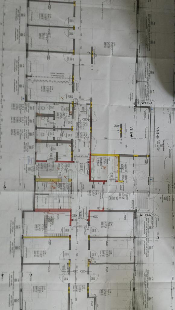 Plan architektoniczny budynku wielorodzinnego z zaznaczonymi wymiarami i układem pomieszczeń, widoczne oznaczenia ścian działowych i nośnych, schemat instalacji elektrycznej i sanitarnej.