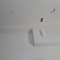 WIBERO Firma Budowlana - Wykończona, biała łazienka w Mielcu z równo ułożonymi, błyszczącymi płytkami, widoczne otwory na oświetlenie i elementy instalacji hydraulicznej oraz narożne półki.