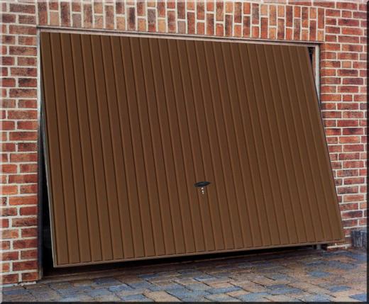 Brązowa segmentowa brama garażowa z pionowymi przetłoczeniami, częściowo otwarta, zamek na środku, widoczna ceglana ściana garażu i fragment kostki brukowej przed wjazdem.