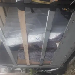 Wnętrze skrzyni ładunkowej z materacem owiniętym folią i meblami zabezpieczonymi kocem, podczas transportu.