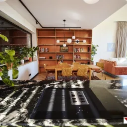 Nowoczesne wnętrze domu z marmurowym blatem kuchennym, widok na stół jadalny, regał z książkami i część wypoczynkową z sofą