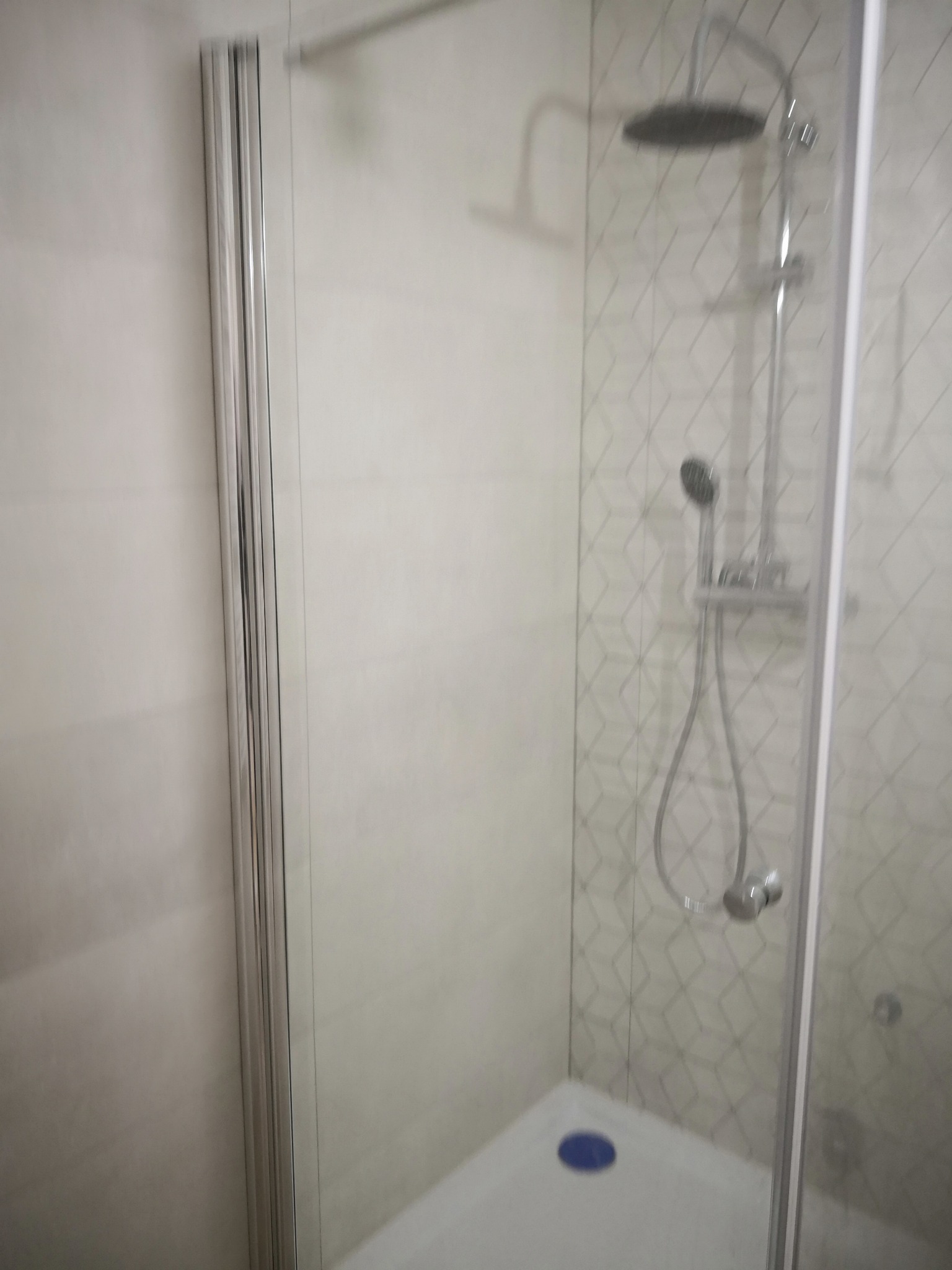 Kabina prysznicowa z deszczownicą i baterią termostatyczną, wykończona płytkami w geometryczny wzór, widok z boku.