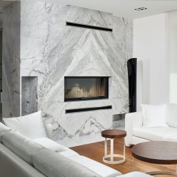 Kominek obłożony marmuru Carrara Bianco w formie lustrzanego odbicia.