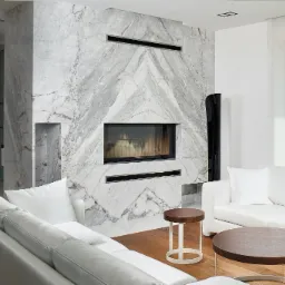 Kominek obłożony marmuru Carrara Bianco w formie lustrzanego odbicia.