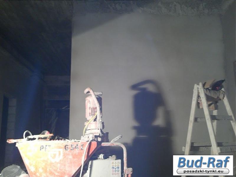 Agregat tynkarski PT-6541 na tle świeżo otynkowanej ściany w trakcie prac wykończeniowych, obok drabina z workiem zaprawy, widoczne logo firmy Bud-Raf w prawym dolnym rogu.