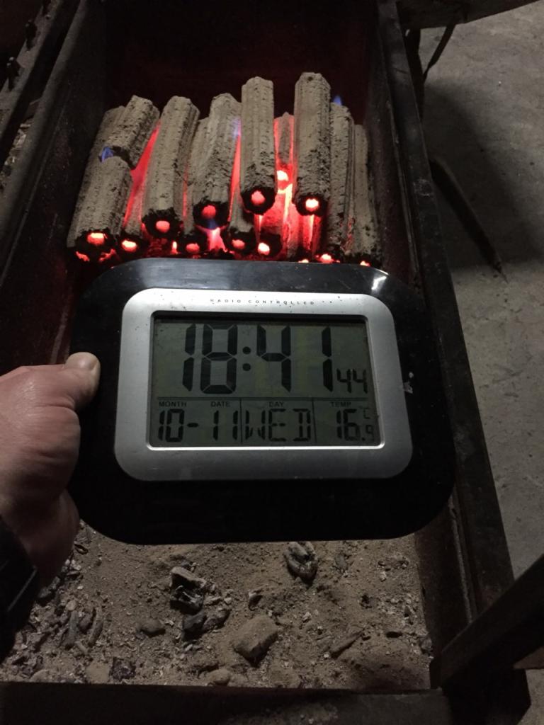 Płonące, perforowane pale węgla drzewnego w palenisku, z elektronicznym zegarem wskazującym datę 10-11, godzinę 18:41 i temperaturę 16.9 stopni Celsjusza.