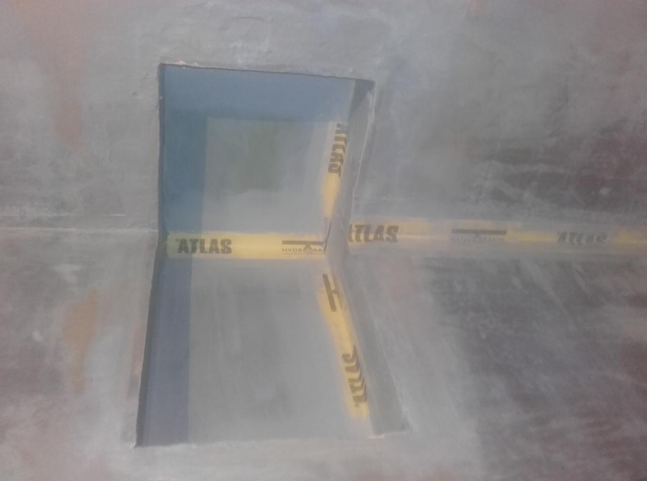 Przygotowanie do położenia płytek w łazience: narożnik zabezpieczony taśmą Atlas Hydro Band, widoczne ślady po szpachlowaniu.